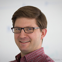 Before circular cropping: medical professional headshot with clinical background and equipment